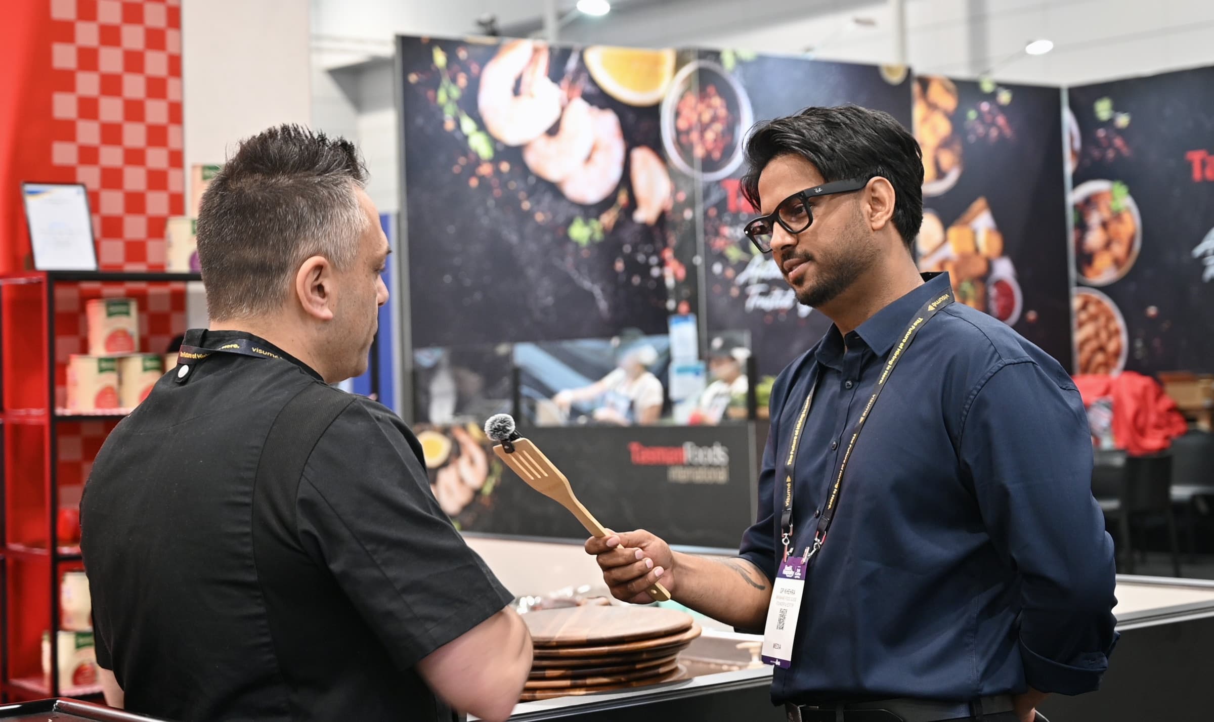 GP Khehra holding a microphone towards Johnny Di Francesco during their conversation at Food and Hospitality Queensland