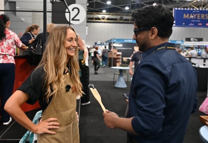 GP Khehra holding a microphone while speaking with Mindy Woods at Food and Hospitality Queensland